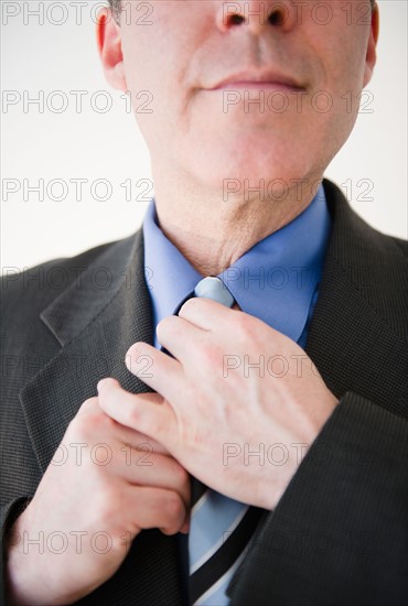 Close up of businessman tying tie. Photo: Jamie Grill