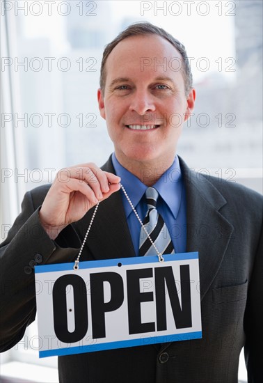 Businessman holding open sign. Photo: Jamie Grill