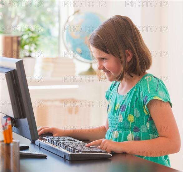 Close up of girl (6-7) using computer in classroom. Photo : Daniel Grill