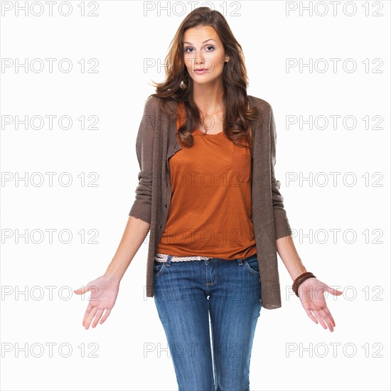 Studio shot of young woman shrugging her shoulders. Photo: momentimages