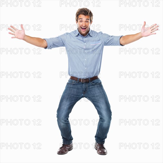 Studio shot of young cheerful man with arms outstretched. Photo: momentimages