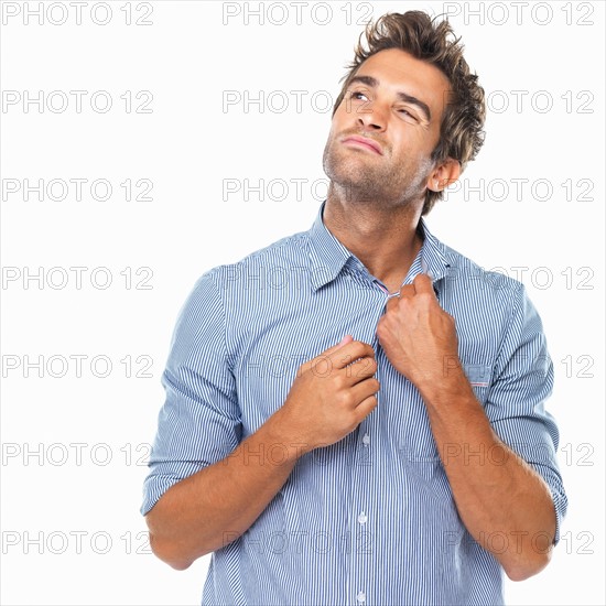 Studio shot of young man unbuttoning shirt. Photo: momentimages