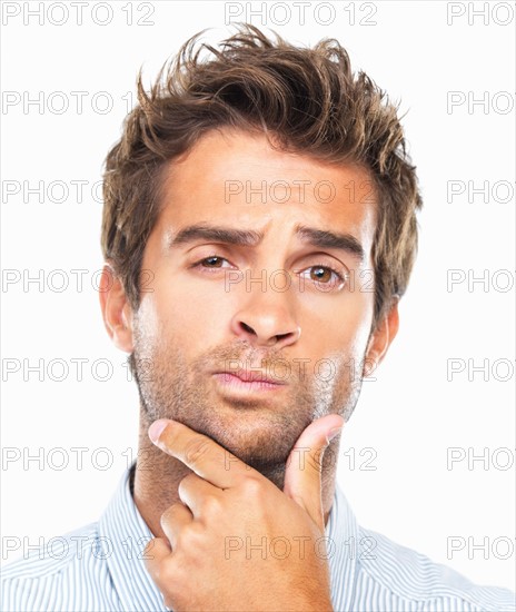 Close-up portrait of confused business man with had on chin against white background. Photo : momentimages