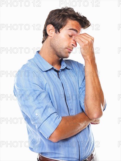 Studio shot of young business man with eyes closed rubbing nose. Photo : momentimages