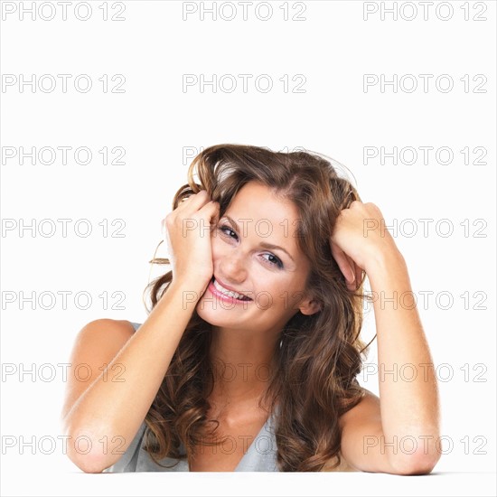 Studio portrait of young woman sitting at table and smiling. Photo : momentimages
