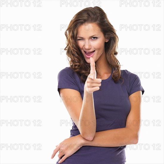 Studio portrait of woman pointing at camera and winking. Photo : momentimages