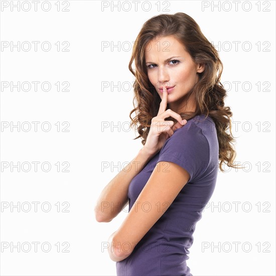 Studio portrait of woman with finger on lips. Photo : momentimages