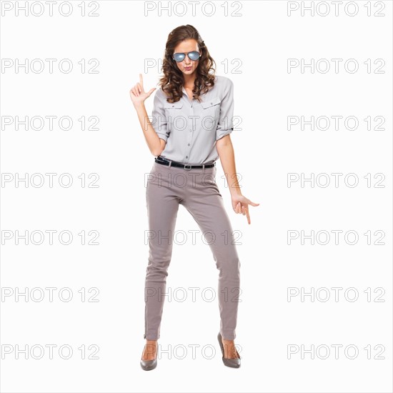 Studio shot of woman with glasses with hands shaped like gun. Photo: momentimages