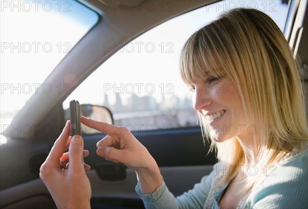 USA, Brooklyn, Williamsburg, Woman using smart phone in car. Photo : Jamie Grill