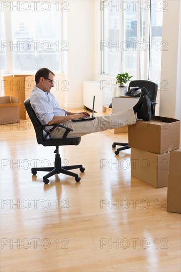 Businessman using laptop in new office.
