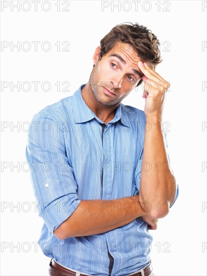 Studio portrait of business man rubbing forehead and looking away. Photo: momentimages