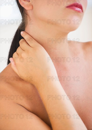 Young woman with hand on neck.