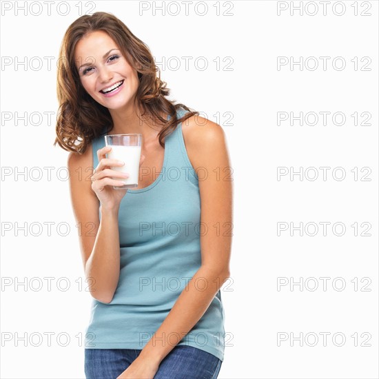 Studio portrait of attractive young woman smiling and holding glass of milk. Photo: momentimages
