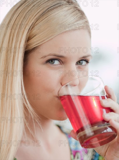 Portrait of young woman drinking juice. Photo: Jamie Grill