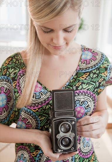 Young woman holding antique camera. Photo : Jamie Grill