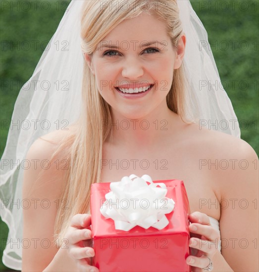 Happy bride holding red box. Photo: Jamie Grill