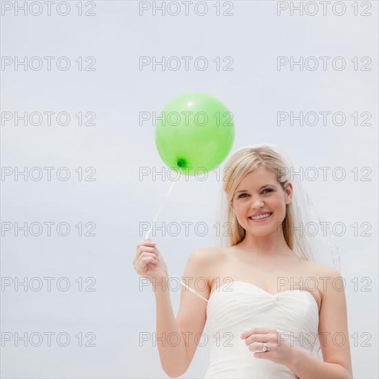 Happy bride holding green balloon. Photo: Jamie Grill