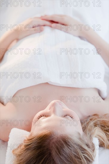 Young woman lying wrapped in towel. Photo : Jamie Grill