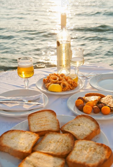 Greece, Cyclades Islands, Mykonos, Calamari appetizer on set table by sea.