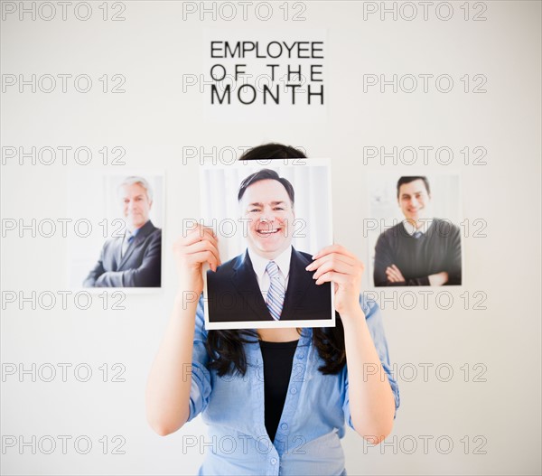 Businesswoman holding photos of men to her face. Photo: Jamie Grill