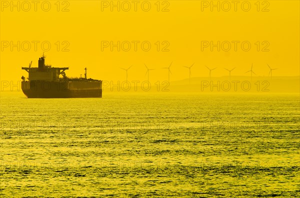 Turkey, Oil tanker on sea with wind turbines in background.