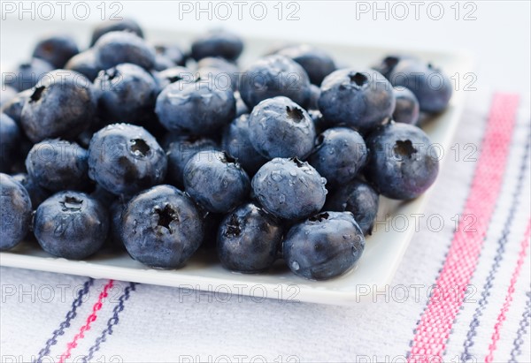 Plate of blueberries on tablecloth.