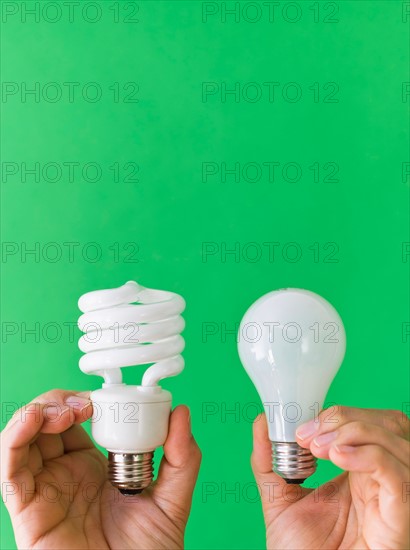 Hands comparing lightbulbs.