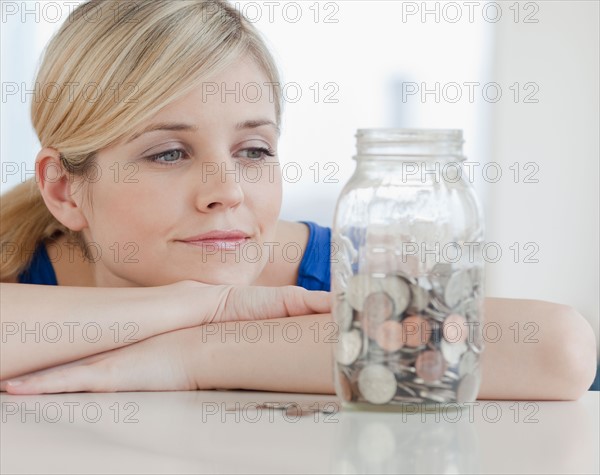 Young woman looking at jar with coins in it. Photo: Jamie Grill