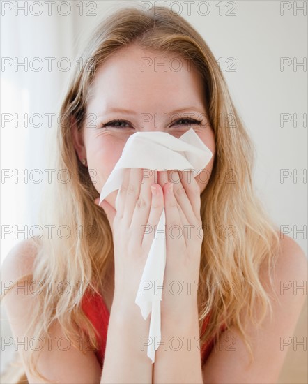 Young woman blowing nose. Photo : Jamie Grill