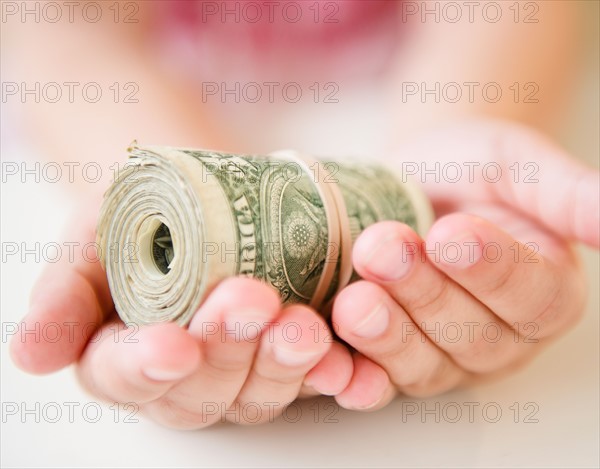 Close up of girl's (8-9) hands holding money roll. Photo : Jamie Grill
