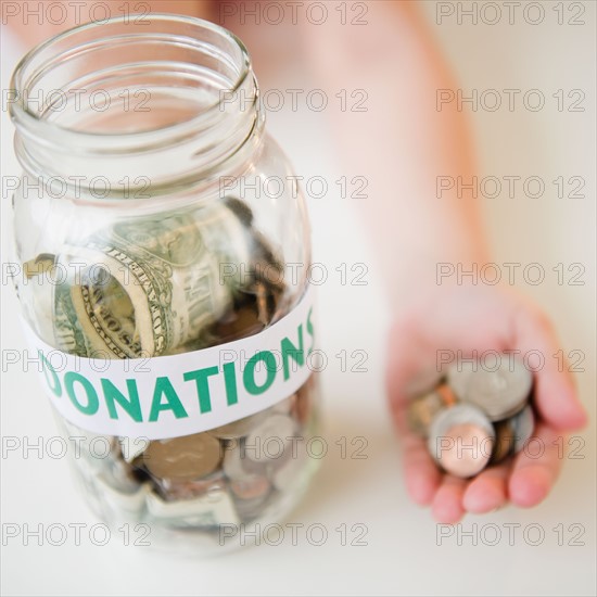 Close up of jar and girl's (10-11) hand holding coins. Photo : Jamie Grill