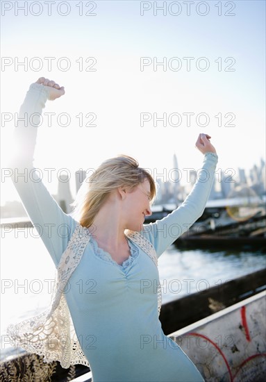 USA, Brooklyn, Williamsburg, Portrait of blonde woman stretching arms in backlit. Photo : Jamie Grill
