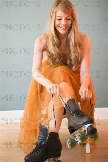 Woman wearing dress and tying roller skates. Photo : Jamie Grill