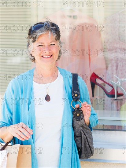 Senior woman standing in front of window display. Photo : Daniel Grill