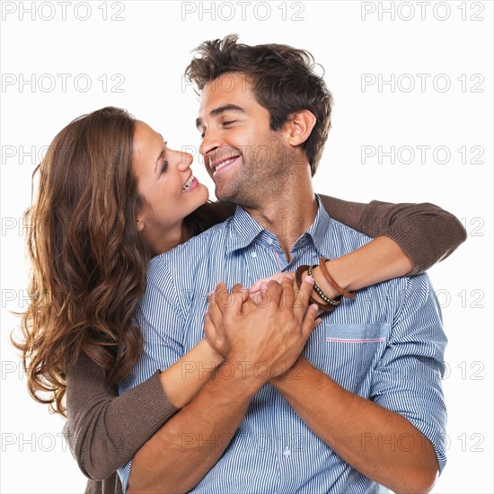 Studio shot of young couple smiling and looking at each other . Photo : momentimages