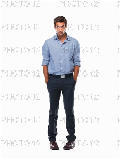 Worried executive standing with hands in pockets against white background. Photo: momentimages