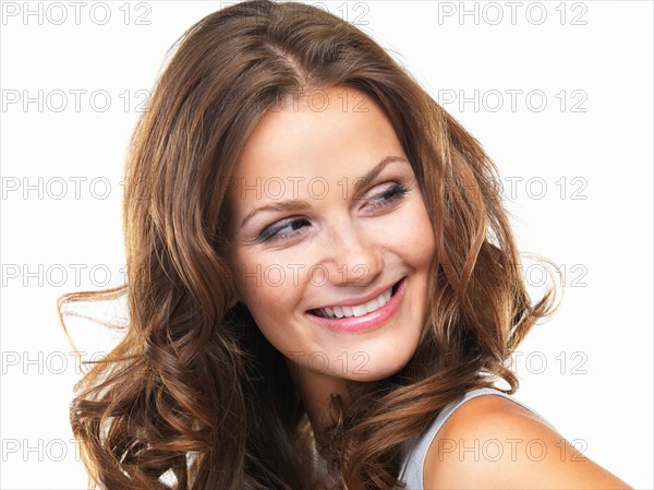 Studio portrait of young woman smiling and looking away. Photo: momentimages
