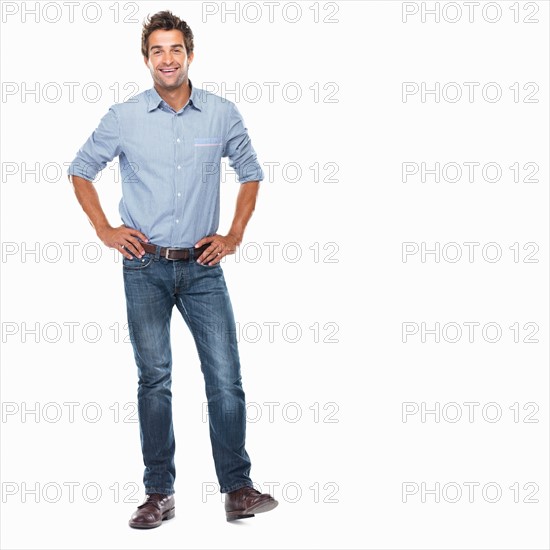Studio shot of young man standing with hands on hips and smiling. Photo : momentimages