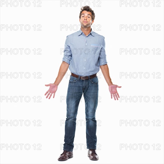 Studio shot of young man with chin up and palms out standing on white background. Photo: momentimages