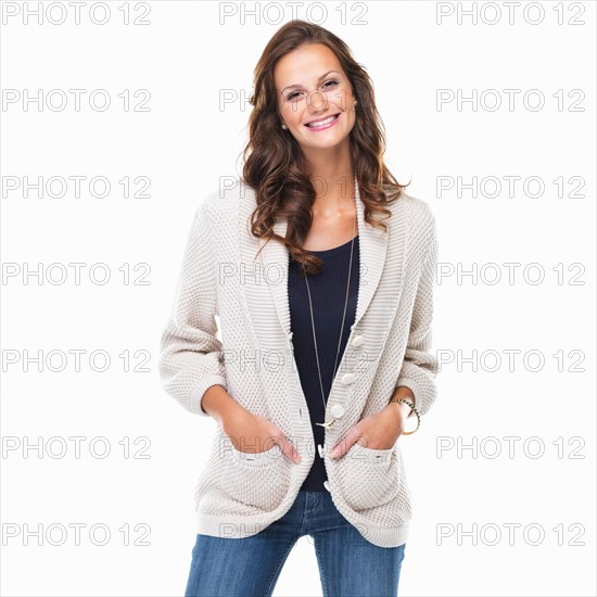 Studio shot of young woman with hands in pockets and smiling. Photo : momentimages