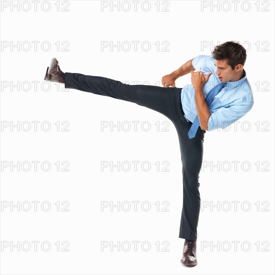 Studio shot of business man delivering high side kick. Photo : momentimages