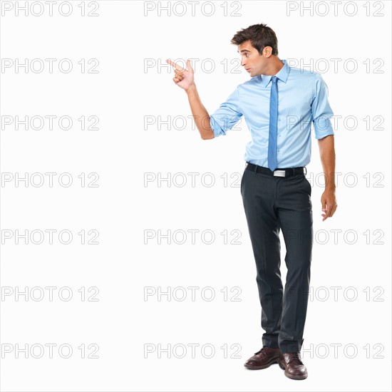 Studio shot of handsome business man pointing at copyspace. Photo : momentimages