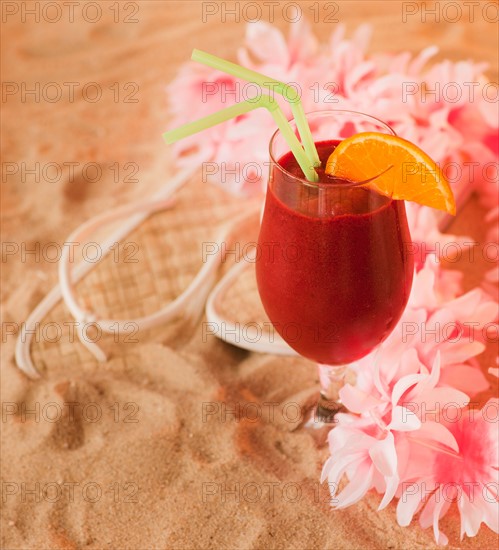 Close up of frozen drink and lei on sand. Photo: Daniel Grill