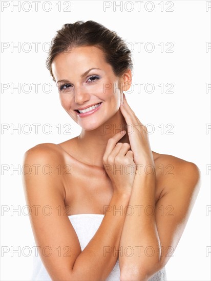 Studio portrait of beautiful woman wrapped in towel touching neck. Photo : momentimages