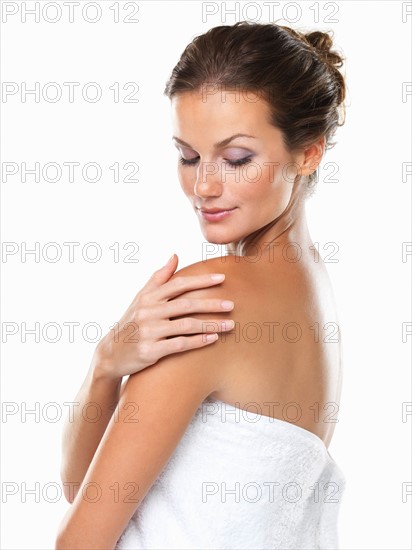 Studio portrait of young attractive woman wrapped in towel with hand on shoulder. Photo : momentimages
