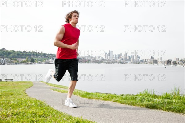 USA, Washington State, Seattle, Young man jogging along river. Photo: Take A Pix Media