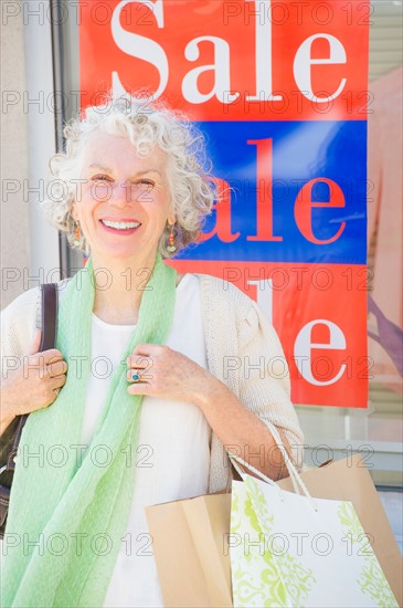 Senior woman standing in front of window display. Photo : Daniel Grill