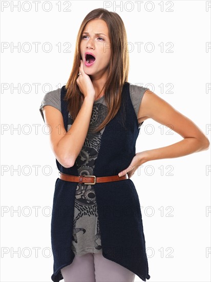 Tired young woman standing and yawning. Photo: momentimages