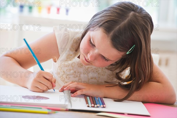 Close up of girl (6-7) drawing in notebook. Photo : Daniel Grill