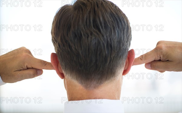 Businessman plugging ears.